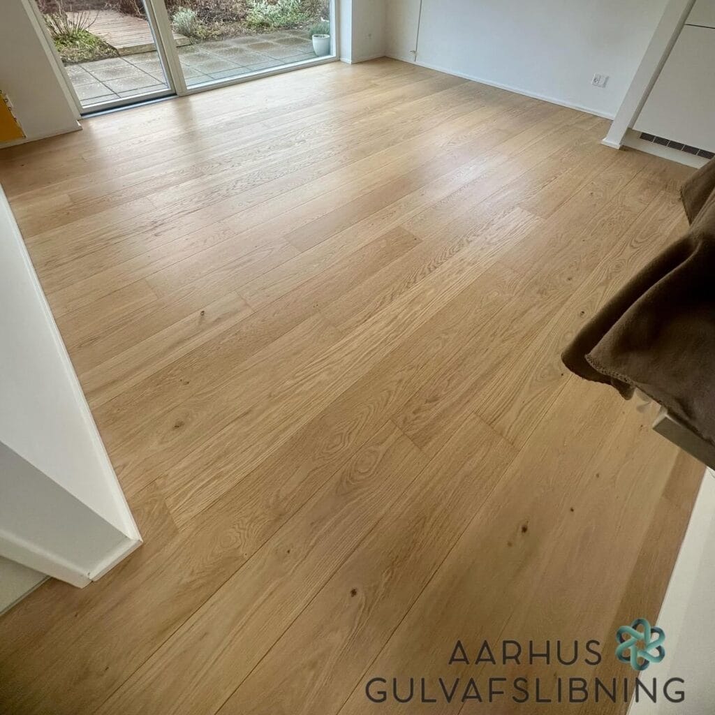 Ny slebet trægulv i stue med store vinduer